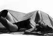© Dmitry Lobanov - Young beautiful brunette woman in black swimsuit or underwear and high boots lying on floor under sexy transparent cloth