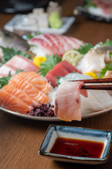 Poster - dipping yellow tail sashimi in soy sauce with chopsticks