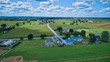 Aerial view of Amish countryside with barns and silos and a one room school house on a sunny summer day