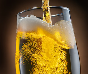 Wall Mural - Jet of beer is poured into a beer glass, causing a lot of bubbles and foam.