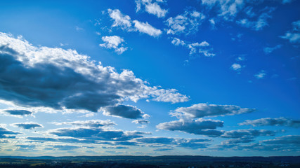 Wall Mural - Blue sky and multiple clouds background showing a horizon and a hidden sun