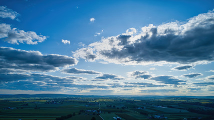 Wall Mural - Blue sky and multiple clouds background showing a horizon and a hidden sun