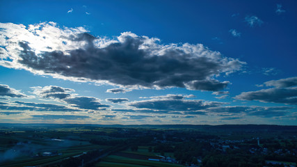 Wall Mural - Blue sky and multiple clouds background showing a horizon and a hidden sun