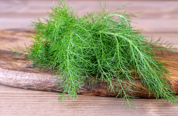 Wall Mural - Bunch of fresh green dill on the wooden background closeup. Aromatic condiment dill for cooking.