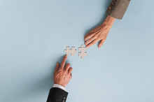 Top View Of Hands Of Businesswoman And Businessman Joining Two  Matching Puzzle Pieces
