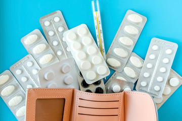 Wall Mural - Empty wallet with white tablets of pills on .blue background.