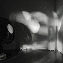 Electric Fan And Electric Lamp On Table Against Wall