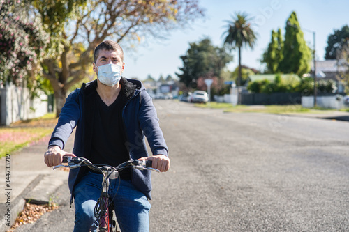 young caucasian man wearing face mask and riding his bicycle on the street Tableau sur Toile