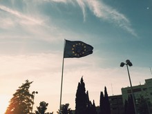 Low Angle View Of European Union Flag By Trees Against Sky During Sunset
