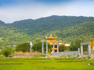 Wall Mural - HOIAN, VIETNAM, SEPTEMBER, 04 2017: Beautiful view of an ancient temple in the horizont, with some green grass in the front, at hoian town in a sunny day in Vietnam