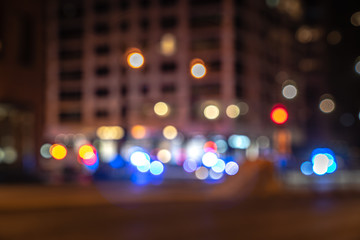 An out of focus cityscape background image of Michigan Avenue in downtown Chicago with red and blue police and ambulance lights at a street corner responding to an emergency blurred in background.