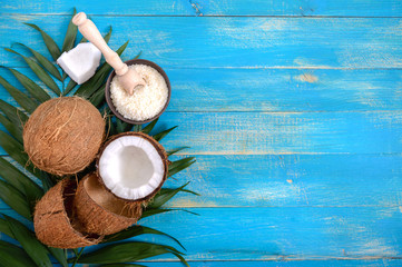 Wall Mural - Whole coconut, shell, green palm leaves on a blue wooden background. Copy space. Top view, flat lay. Tropical background.