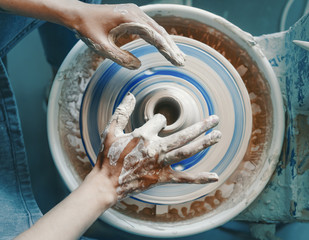 Close-up of female hands sculpting clay on a Potter's wheel. Concept of hobby and cretivity at home and in the Studio workshop