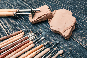 Flat top view of a set of various tools for working and carving raw clay for pottery. Concept of a hobby and a pleasant creative pastime in the house and workshop