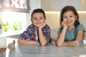 Wall Mural - Cute little children at table with cooking ingredients in kitchen