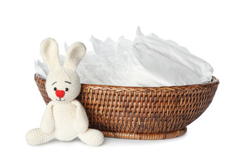 Wall Mural - wicker bowl with disposable diapers and toy bunny on white background