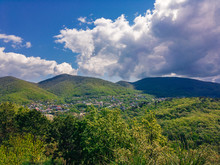 Mountains Covered With Green Vegetation On A Sunny Day Against A Blue Sky With Cumulus Clouds.