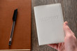 © yuriygolub - Hand holding a passport. Books in the background