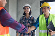 © khwanchai - Handshake of two business man, after architect working and planning blueprint, Engineering objects on workplace