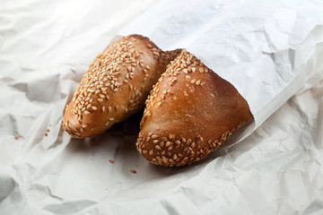 Baguette with sesame seeds on the background of mint white paper