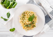 pasta with spinach and cheese on a plate, fork, fresh spinach leaves, top view