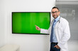 © W PRODUCTION - man male doctor professor teacher in medical office wearing a white lab coat and tie shirt showing to students green wall srceen research covid19 and coronavirus seminar