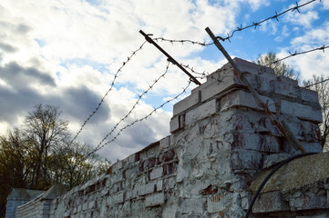 Beautiful white painted brick wall shabby old with cracks in the loft style with seams and barbed wire against the blue sky. Texture, background