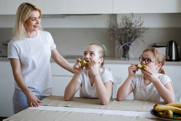 Mom and two daughters in white at the table.