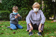 © progat - Grandmother and little kid playing with a smartphone in the backyard while wearing protective masks due to coronavirus outbreak