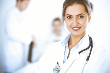 Wall Mural - Female doctor smiling on the background with patient in the bed and two doctors