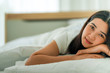 © ake - young asian woman lying on the bed under the clean white quilt both hands under the head resting stay home self quarantine during the covid-19 norona virus pandemic for social distancing