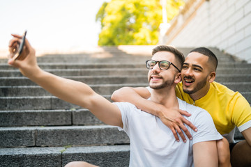 Wall Mural - Gay couple taking a selfie with mobile phone.