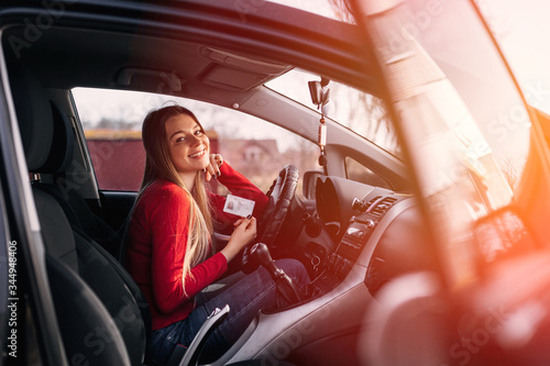 Cuadros en Lienzo Portrait of a beautiful young woman sits in car with driver's license