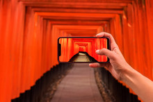 Tourist Taking A Picture Of Orange Wooden Pillars In Kyoto, Japan