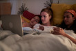 © guille Faingold/Stocksy - Three girls lying in bed streaming media content on laptop at home