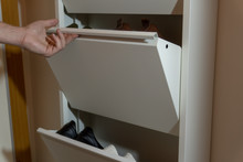A Man Taking His Shoes Off A Layered Mechanical Shoe Cabinet - Close Up