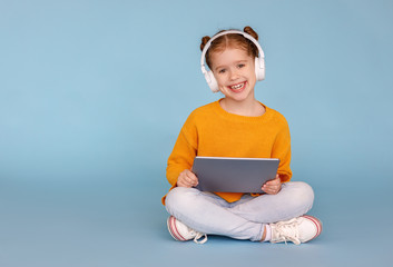 Wall Mural - Cheerful girl in headphones browsing tablet