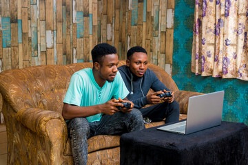 Wall Mural - young black men playing a video game on a laptop at home