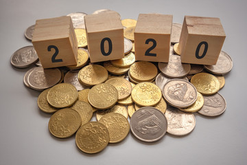 Year 2020 concept with wooden cube on scattered coins