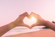 Female Hands In The Form Of Heart Against Sunlight In Sunset Sky On Beach Summer. Hands In Shape Of Love Heart, Love Concept.