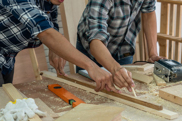 Carpenter working on wood craft at workshop to produce construction material or wooden furniture. The young Asian carpenter use professional tools for crafting. DIY maker and carpentry work concept.