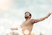 Happy Traveler Male Embracing Life And Enjoying Freedom With Open Arms Over Sky And Bokeh Effect. Carefree Smiling Bearded Man Standing Relaxing And Breathing Fresh Nature Air At Outdoor. Healthy Life