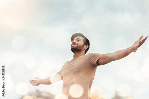 Fotomural Happy Traveler male embracing life and enjoying freedom with open arms over sky and bokeh effect