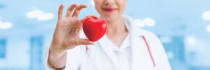 Doctor holding a red heart at hospital office. Medical health care and doctor staff service to fight Coronavirus and COVID-19.