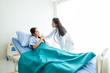 © Thinapob - Asian young female patient on bed showing thumbs up with smiley face very good symptom to asian young female doctor in hospital background.