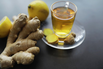 Ginger root whole and sliced. Ginger tea with lemon on the dark background. Fresh ginger root on stone background. Vitamins. Free space for your text.