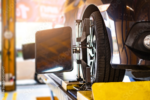 Obraz Dibond mechanik samochodowy pracujący nad naprawą opony koła pojazdu, oddający samochód do warsztatu serwisowego dla męskich mechaników samochodowych, naprawiający problemy z wymianą zepsutych części używania narzędzi i sprzętu