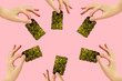 Frame of female hands with crispy seaweed on the pink background with copy space. Dry nori sheets korean or japanese texture. Flat lay. Healthy food concept.