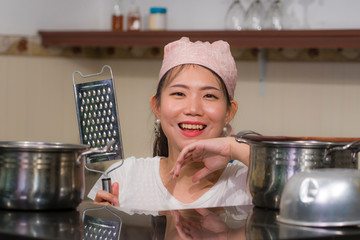 Sticker - young beautiful and happy Asian Chinese woman in head scarf at home kitchen smiling happy and relaxed enjoying cooking looking at camera posing with pot and houseware