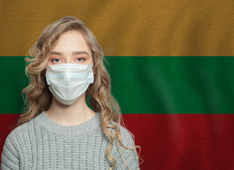 Wall Mural - Young woman wearing a face mask with Lithuanian  flag. Flu epidemic and virus protection concept